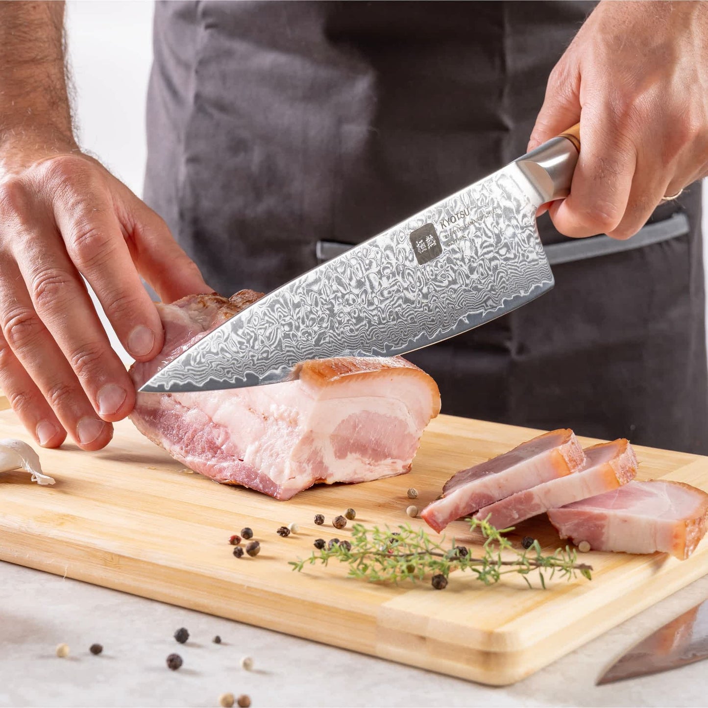 Eine Person schneidet mit dem Kyotsu Chefmesser aus Damaststahl Fleisch auf einem Holz-Schneidebrett – hochwertiges Messer in Aktion.