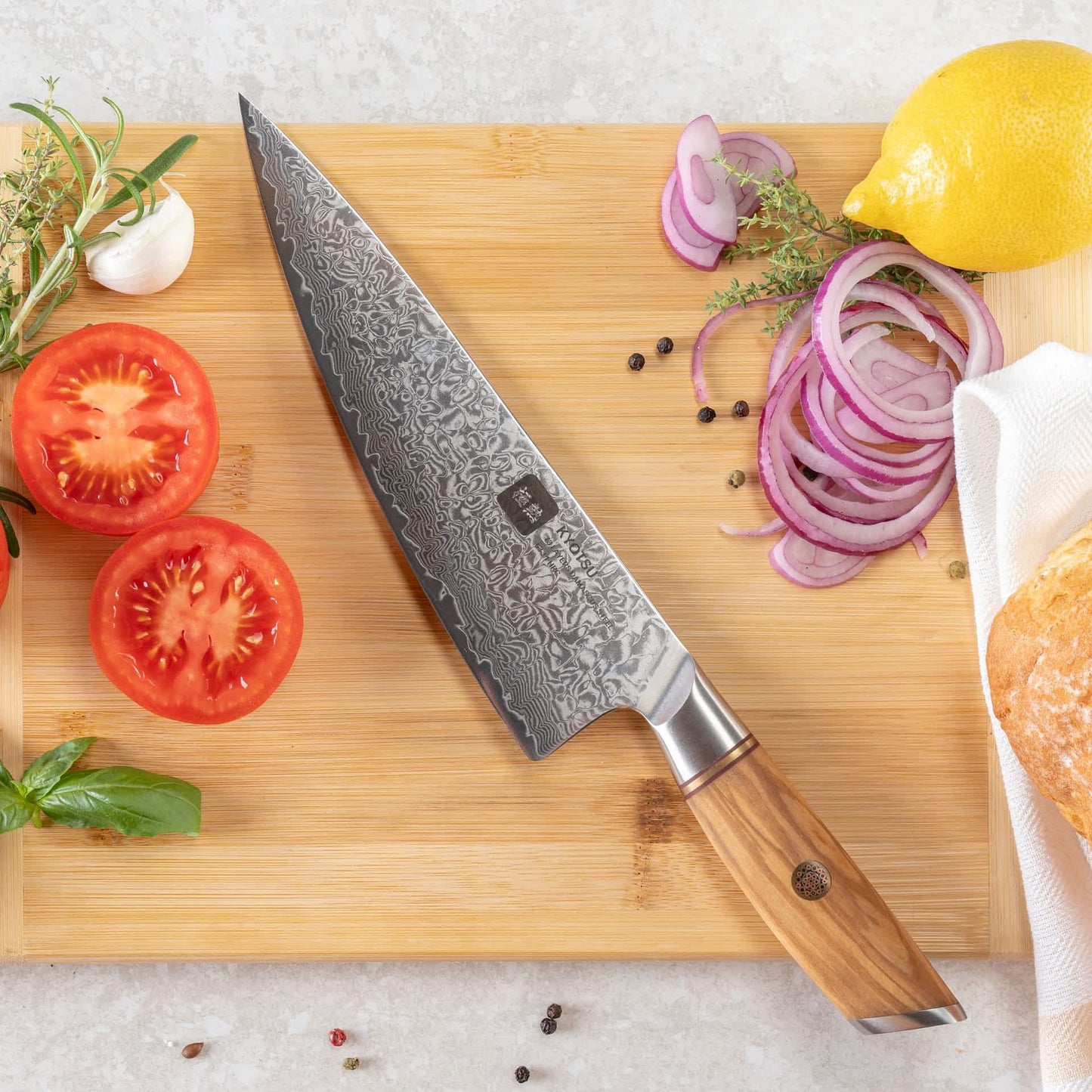 Kyotsu Chefmesser aus Damaststahl auf Holz-Schneidebrett mit frischen Zutaten – stilvolle Produktpräsentation für hochwertige Küchenmesser.