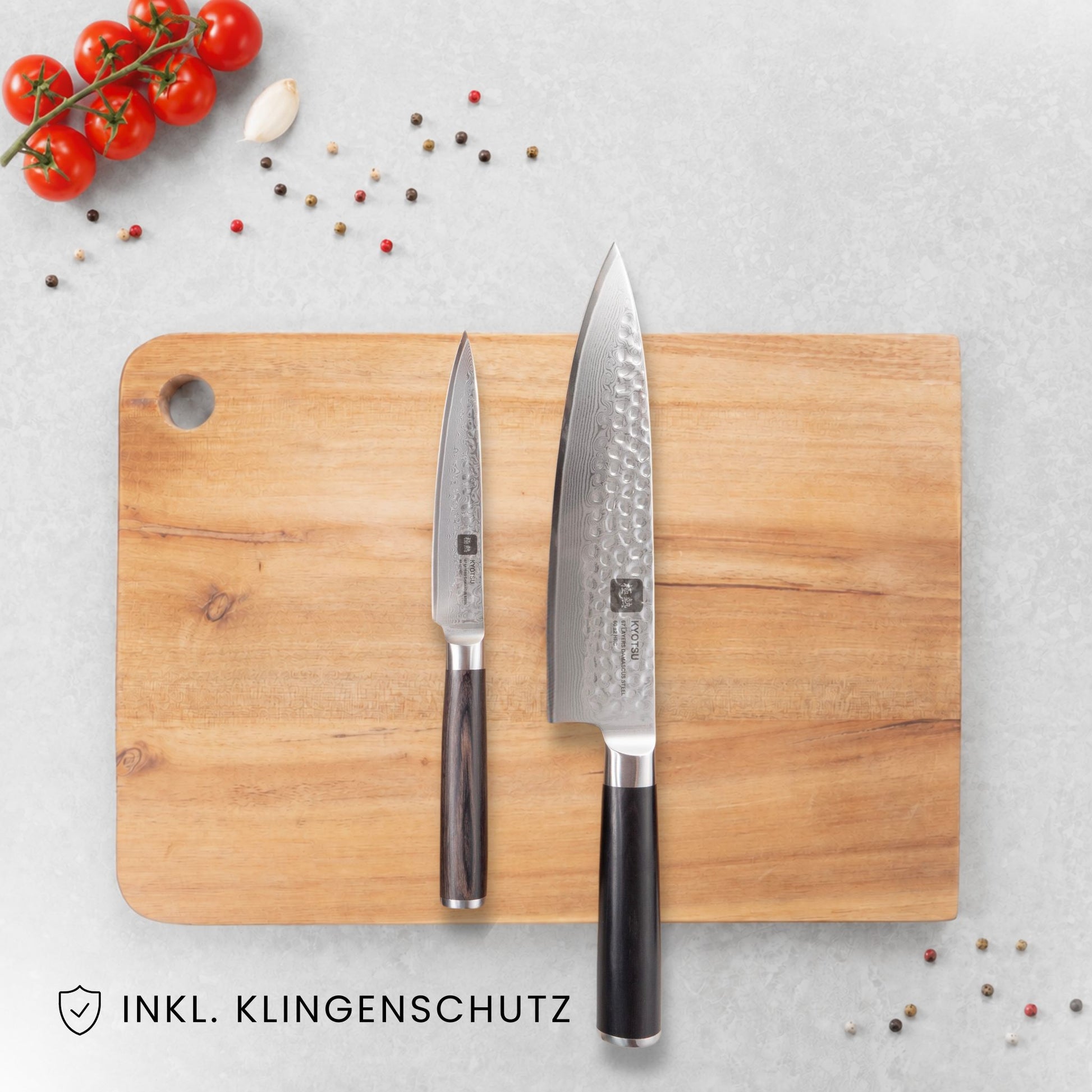 Kyotsu 2er-Set Pakka: Allzweckmesser und Chefmesser liegen auf einem Holz-Schneidebrett, daneben frische Zutaten.