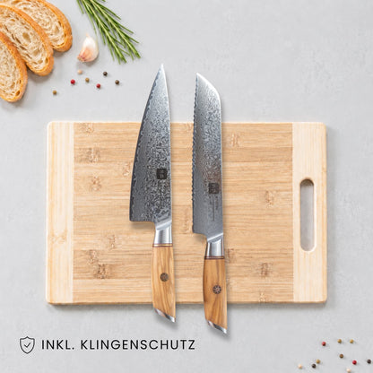 Kyotsu 2er-Set: Chefmesser und Brotmesser liegen auf einem Holz-Schneidebrett, daneben frische Zutaten.