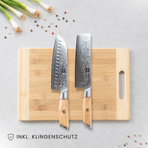 Kyotsu 2er-Set Olive: Santoku-Messer und Nakiri-Messer liegen auf einem Holz-Schneidebrett, daneben frische Zutaten.