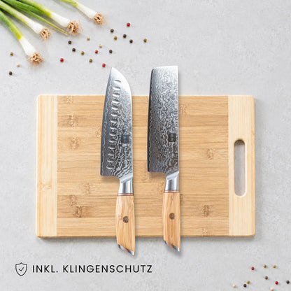 Kyotsu 2er-Set: Santoku-Messer und Nakiri-Messer liegen auf einem Holz-Schneidebrett, daneben frische Zutaten.
