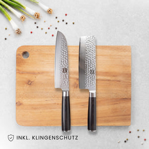 Kyotsu 2er-Set Pakka: Santoku-Messer und Nakiri-Messer liegen auf einem Holz-Schneidebrett, daneben frische Zutaten.
