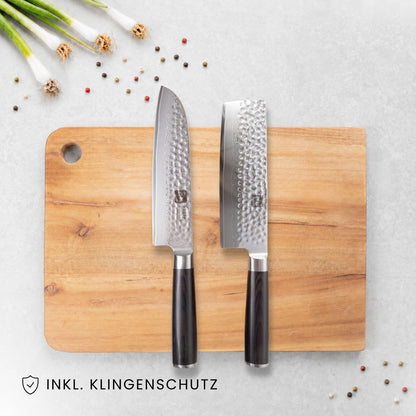 Kyotsu 2er-Set Pakka: Santoku-Messer und Nakiri-Messer liegen auf einem Holz-Schneidebrett, daneben frische Zutaten.