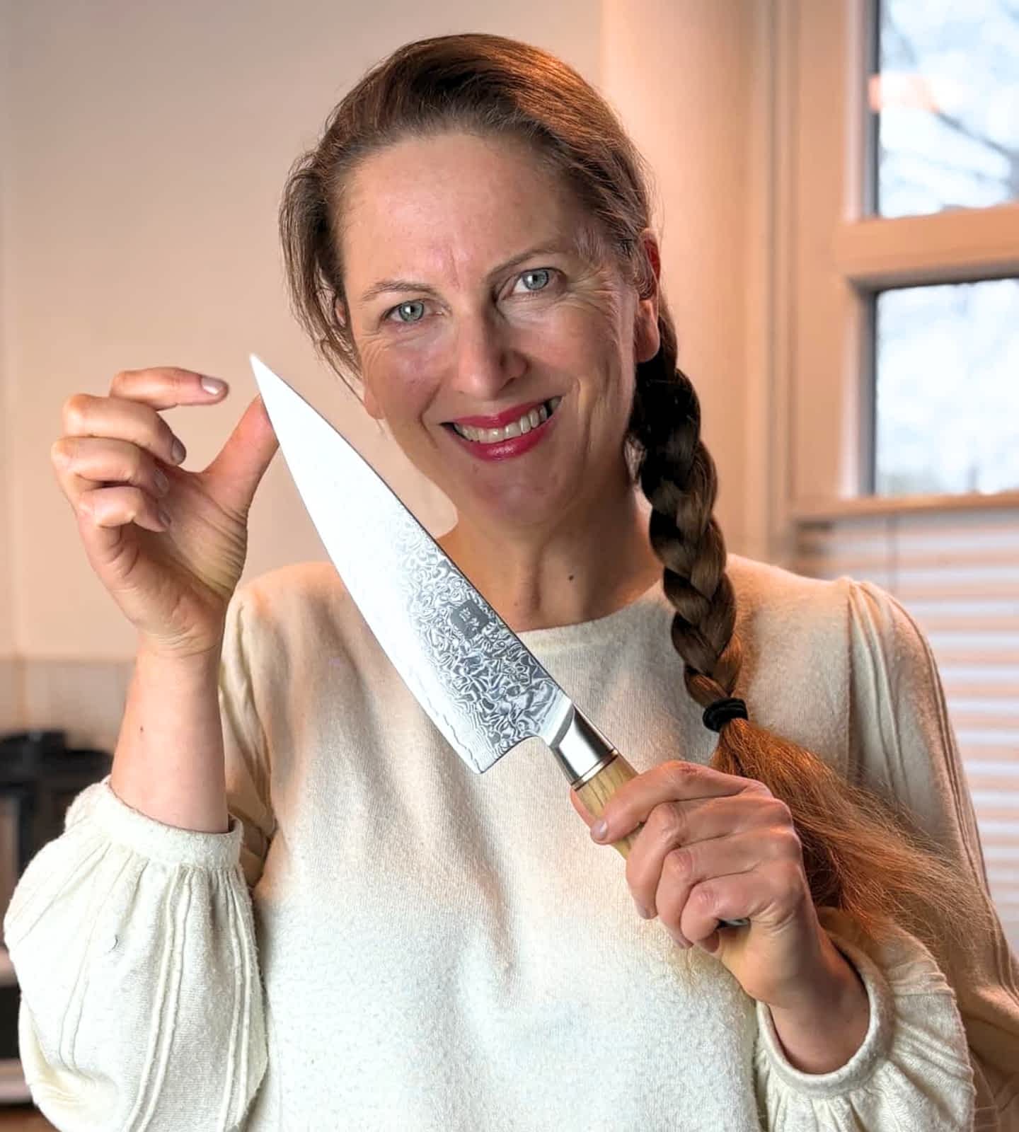Eine Frau zeigt glücklich das Chefmesser von Kyotsu und lächelt in die Kamera.