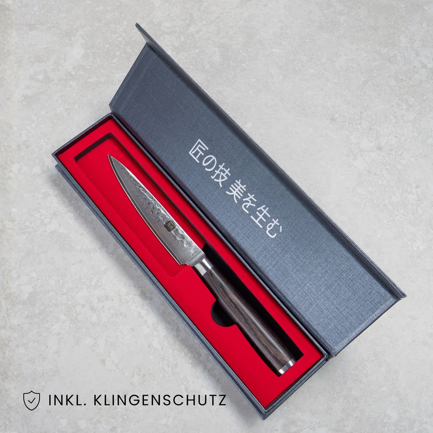 Kyotsu Allzweckmesser aus Damaststahl in geöffneter Verpackung, unten Links der Schriftzug "Inkl. Klingenschutz".