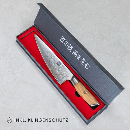 Kyotsu Chefmesser aus Damaststahl in geöffneter Verpackung, unten Links der Schriftzug "Inkl. Klingenschutz".