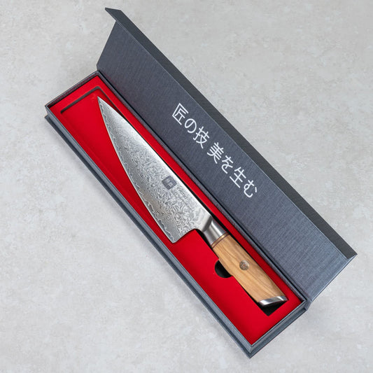 Kyotsu Chefmesser aus Damaststahl in geöffneter Verpackung.
