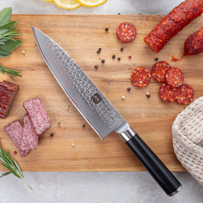Kyotsu Chefmesser aus Damaststahl auf Holz-Schneidebrett mit frischen Zutaten – stilvolle Produktpräsentation für hochwertige Küchenmesser.