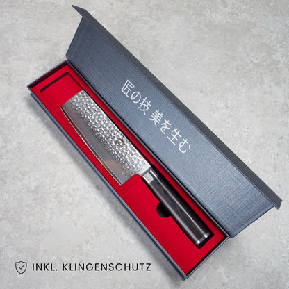 Kyotsu Nakiri-Messer aus Damaststahl in geöffneter Verpackung, unten Links der Schriftzug "Inkl. Klingenschutz".