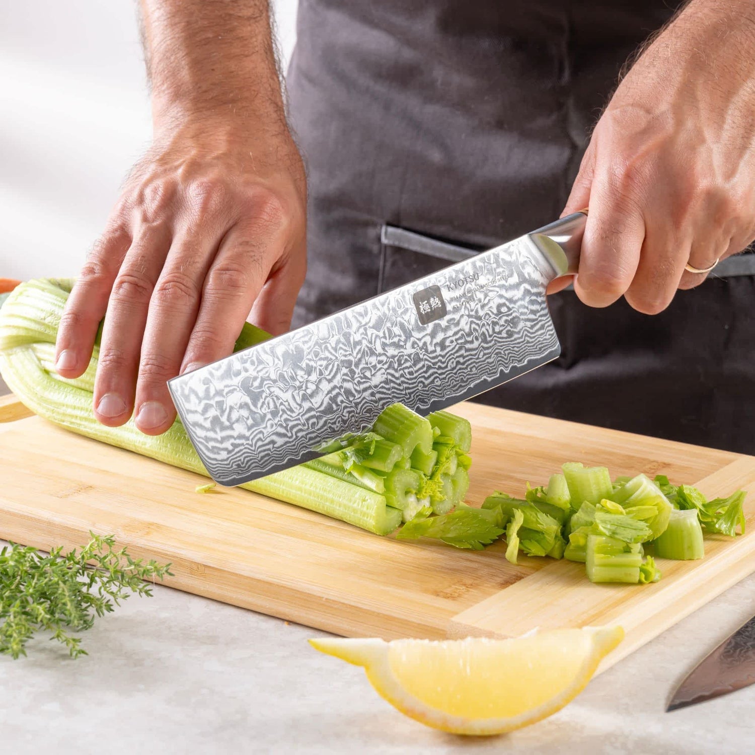 Eine Person schneidet mit dem Kyotsu Nakiri-Messer aus Damaststahl Gemüse auf einem Holz-Schneidebrett – hochwertiges Messer in Aktion.