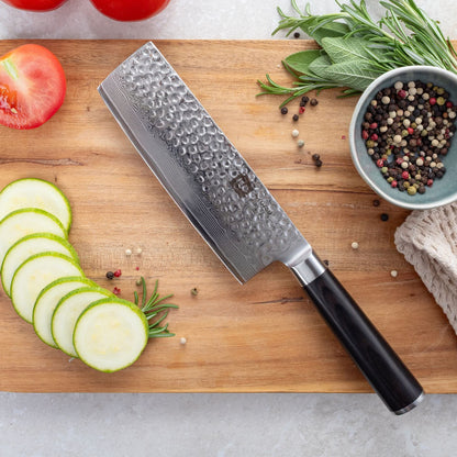 Kyotsu Nakiri-Messer aus Damaststahl auf Holz-Schneidebrett mit frischen Zucchini und Tomaten – stilvolle Produktpräsentation für hochwertige Küchenmesser.