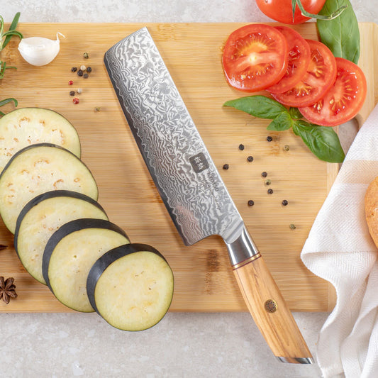 Kyotsu Nakiri-Messer aus Damaststahl auf Holz-Schneidebrett mit frischen Auberginen und Tomaten – stilvolle Produktpräsentation für hochwertige Küchenmesser.