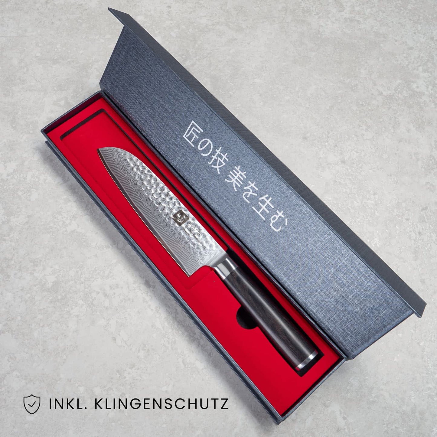 Kyotsu Santoku-Messer aus Damaststahl in geöffneter Verpackung, unten Links der Schriftzug "Inkl. Klingenschutz".