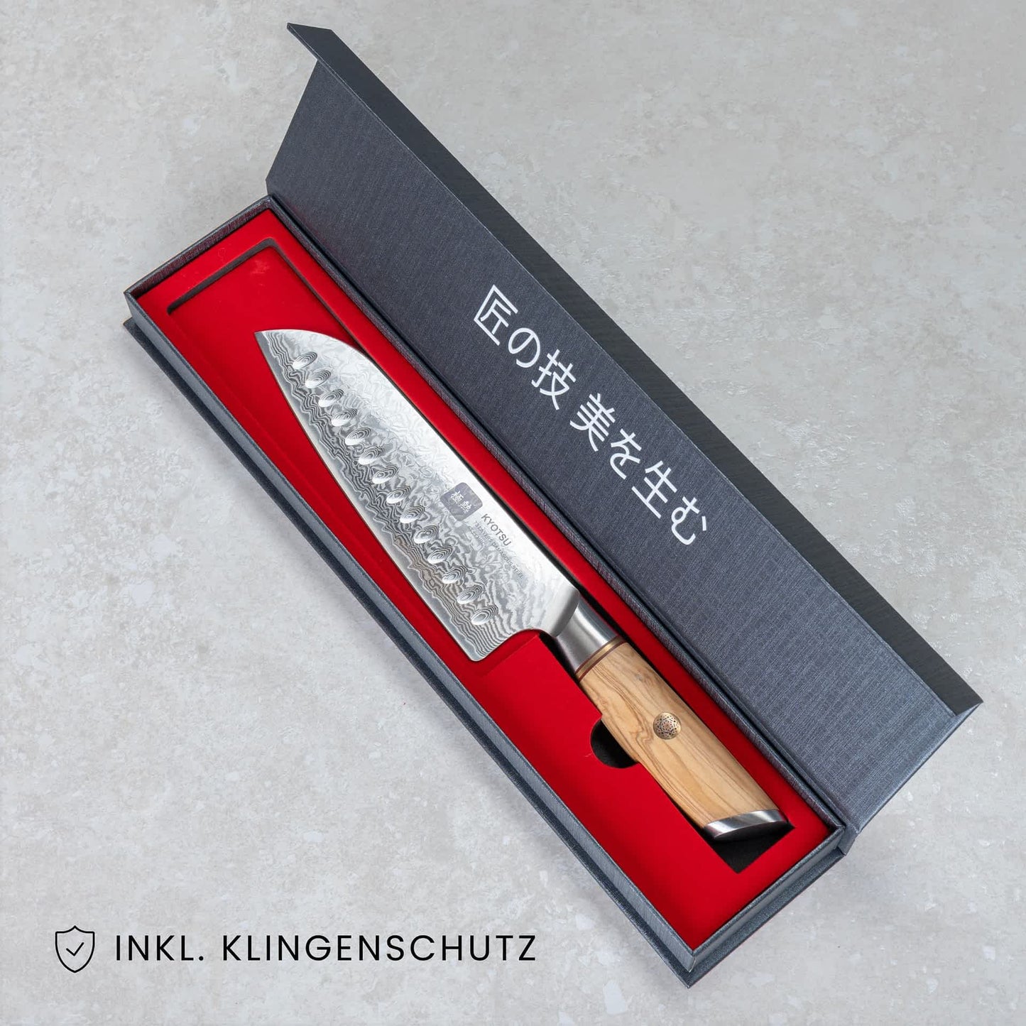 Kyotsu Santoku-Messer aus Damaststahl in geöffneter Verpackung, unten Links der Schriftzug "Inkl. Klingenschutz".