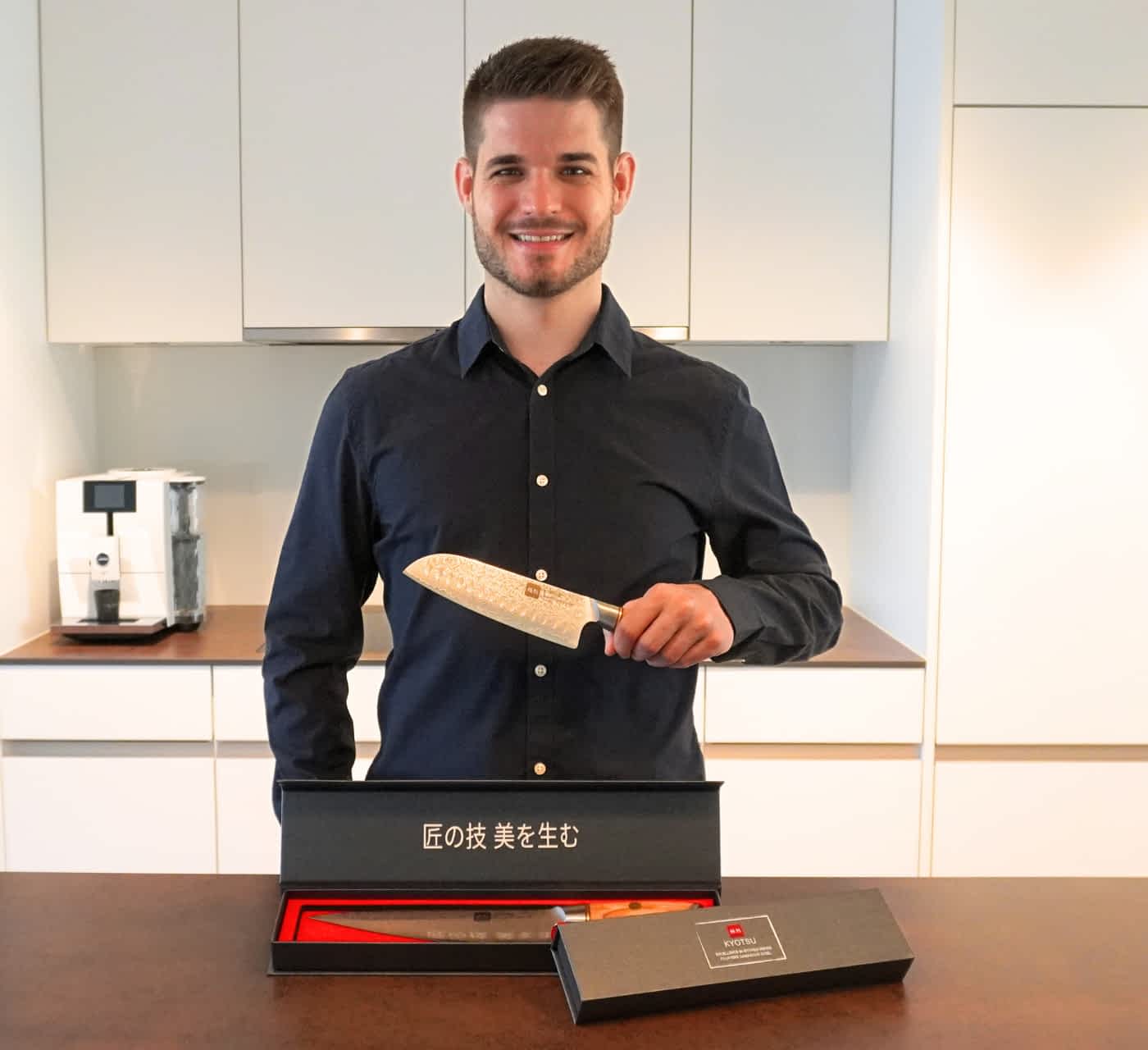 Foto des Gründers Tobias mit den Kyotsu Damastmessern, Foto aufgenommen in einer Küche.