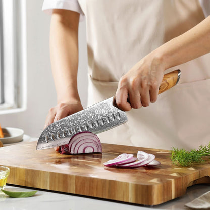 Eine Person schneidet mit dem Kyotsu Santoku-Messer aus Damaststahl Zwiebeln auf einem Holz-Schneidebrett – hochwertiges Messer in Aktion.