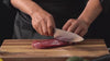 Video eines Koches beim Gebrauch des Kyotsu Chefmesser. Er schneidet Fleisch, Gemüse und mehr kinderleicht.